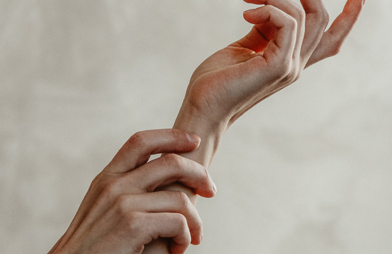 Psoriasis_SChuppenflechte_RAU-02 Hände, die an einem Handgelenk kratzen, symbolisieren Juckreiz und Hautirritationen, relevant für die Diskussion über Psoriasis und Hautpflegeprodukte von RAU Cosmetics.