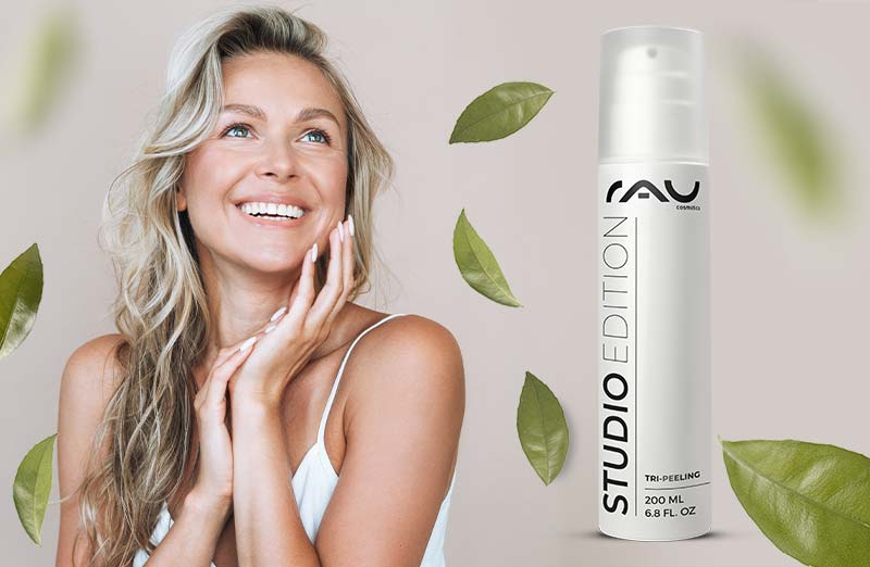 „Lächelnde weibliche Model mit wavy Haar neben einem modernen RAU Tri-Peeling-Flasche und grünen Blättern.“