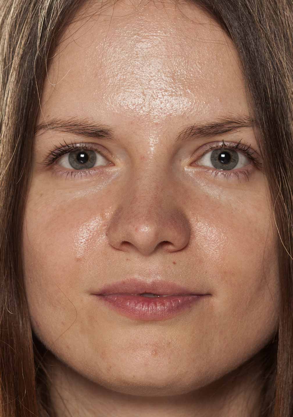 Junge Frau mit klarem Gesicht und neutralem Ausdruck, ideal für Hautpflegeprodukte bei RAU Cosmetics.