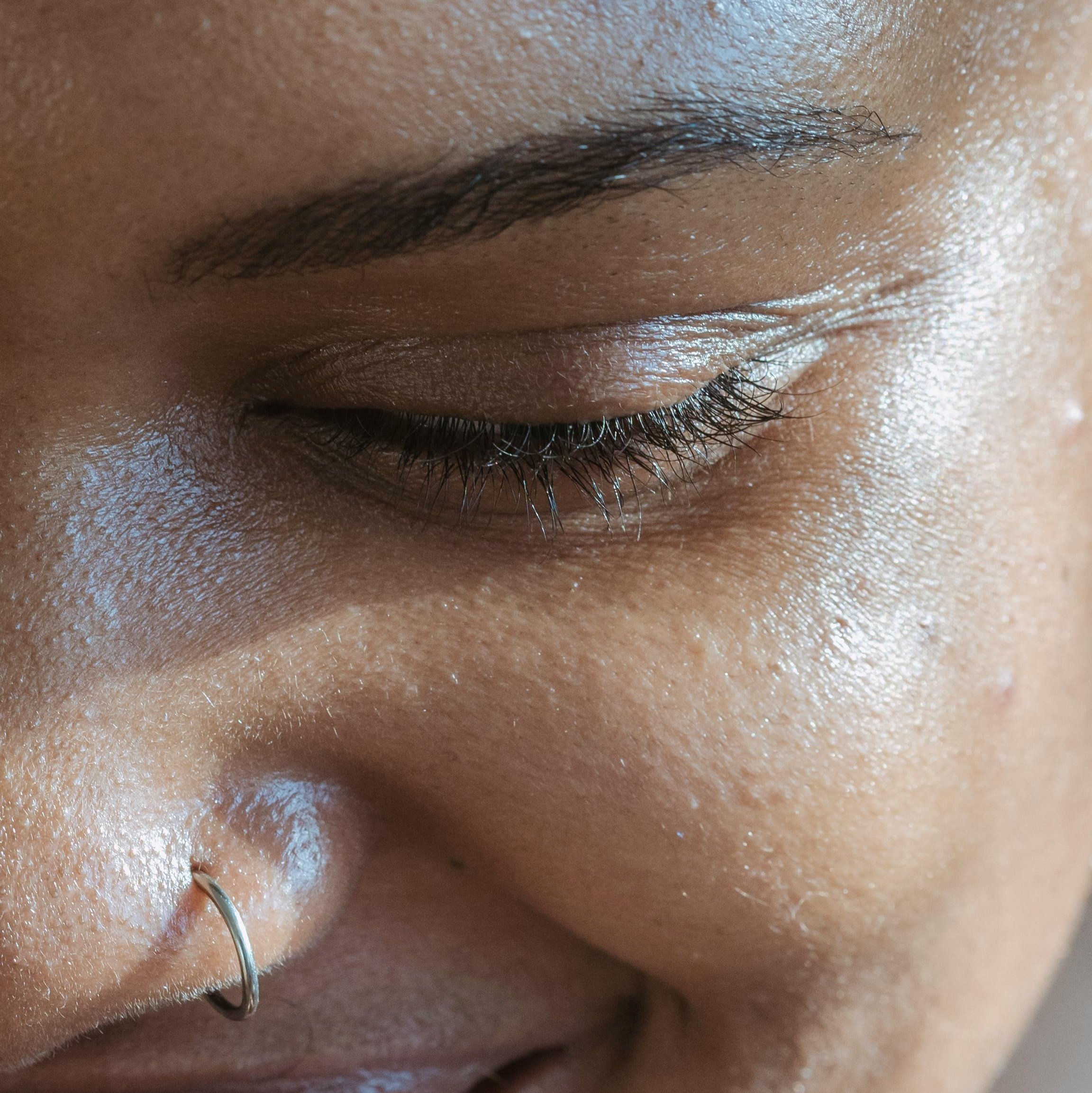 Nahaufnahme eines Gesichts mit sichtbaren Hautunreinheiten und einem Nasenpiercing, betont die Herausforderungen bei der Hautpflege und die Notwendigkeit effektiver Produkte zur Bekämpfung von Mitessern.