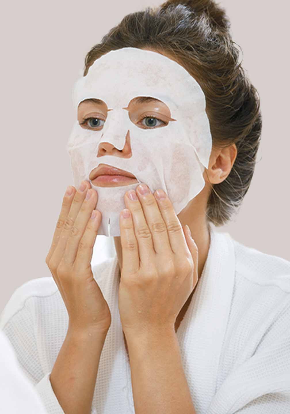 Frau mit einem Sheet-Mask im Spiegel, entspannend in einem Badezimmer für RAU Cosmetics Hautpflegeprodukte.